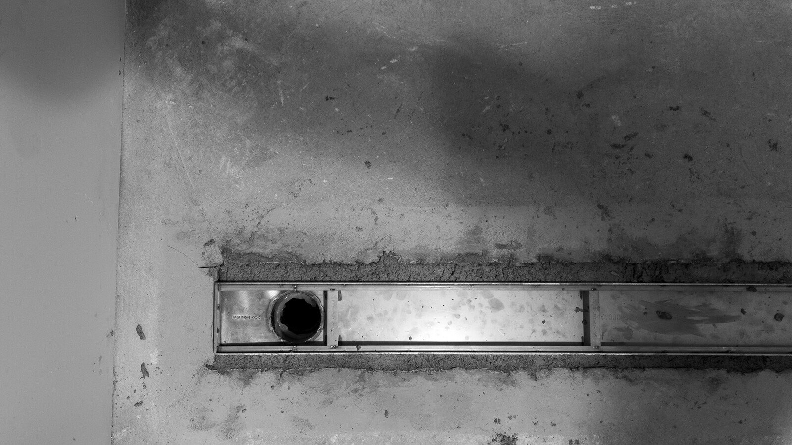 Frost stainless steel linear drain positioned in a Wembley Stadium shower room.